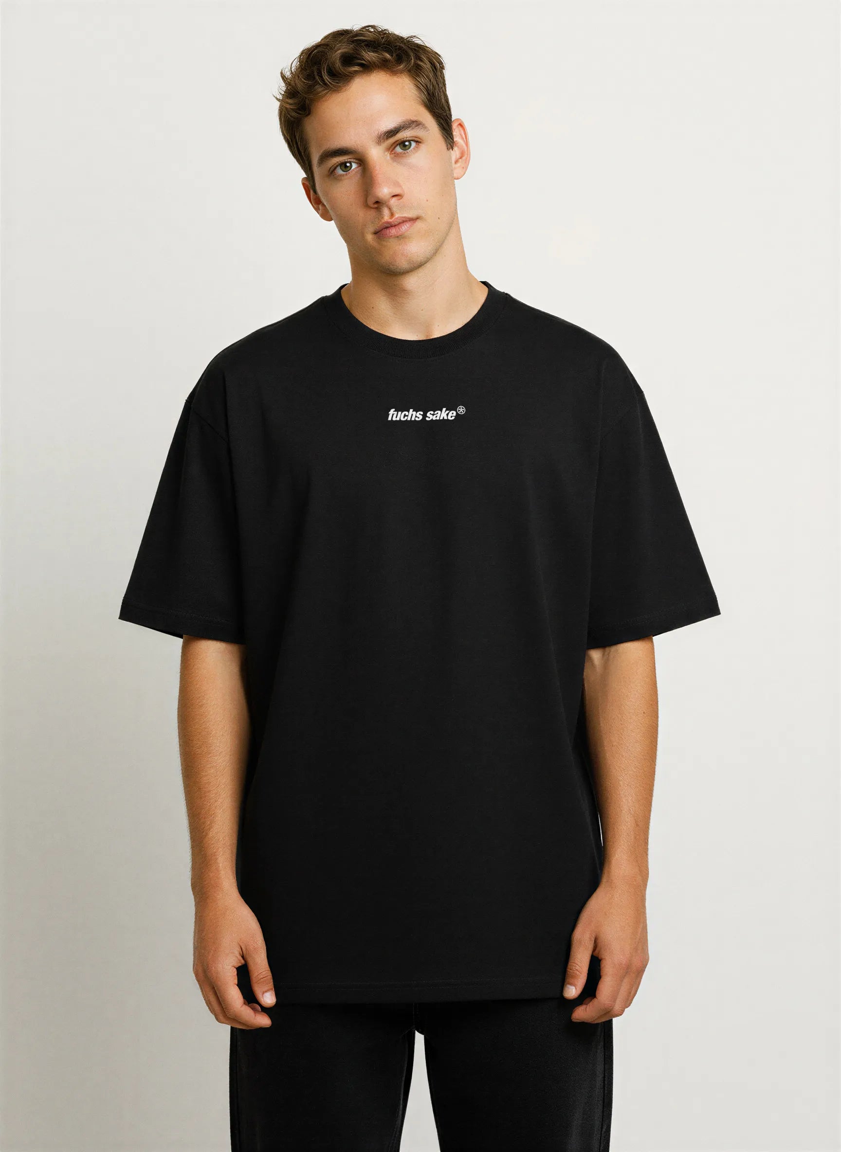 Front view of man modeling black ‘fuchs sake’ T-shirt with minimalist chest logo — premium streetwear for Porsche and Fuchs wheel enthusiasts.