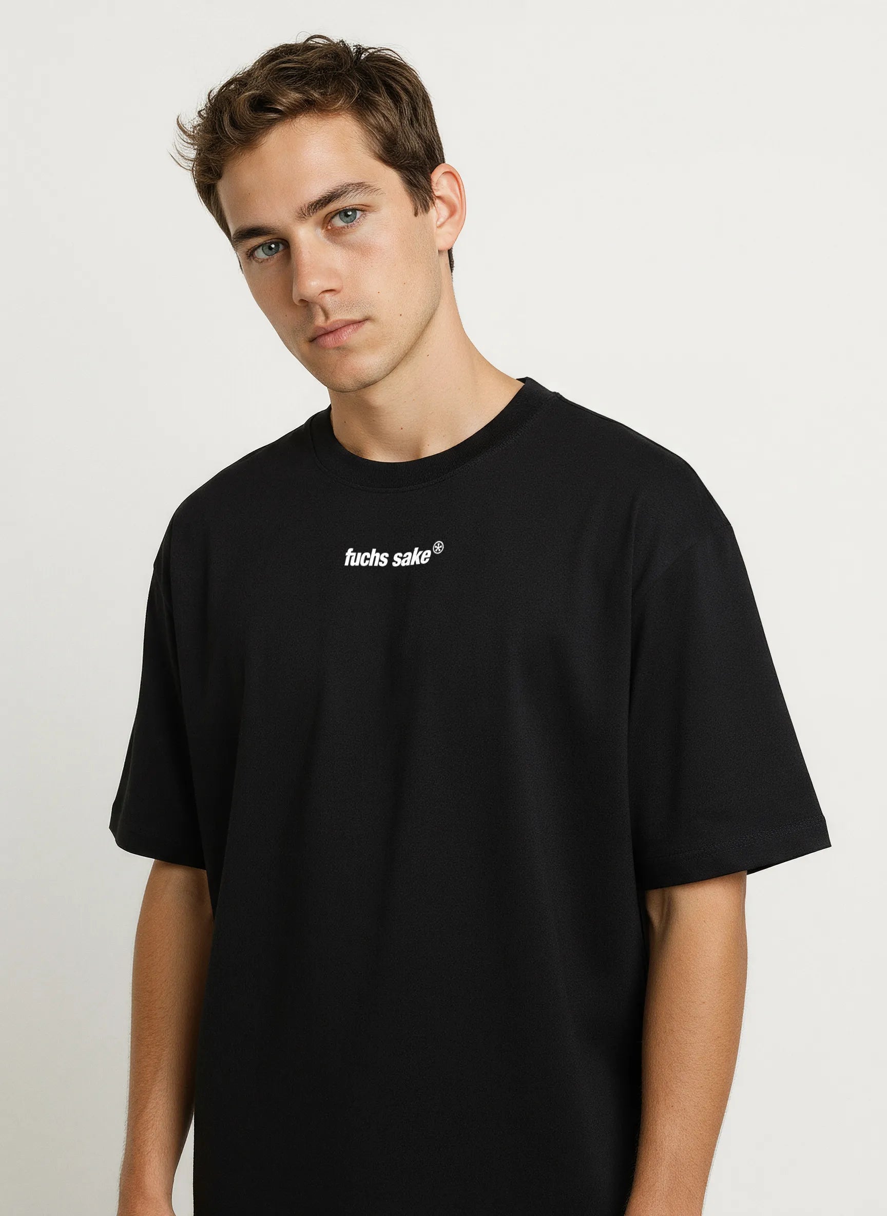 Angled front view of man in casual outfit wearing black ‘fuchs sake’ tee — stylish automotive-inspired clothing celebrating Porsche’s classic Fuchs wheel design.