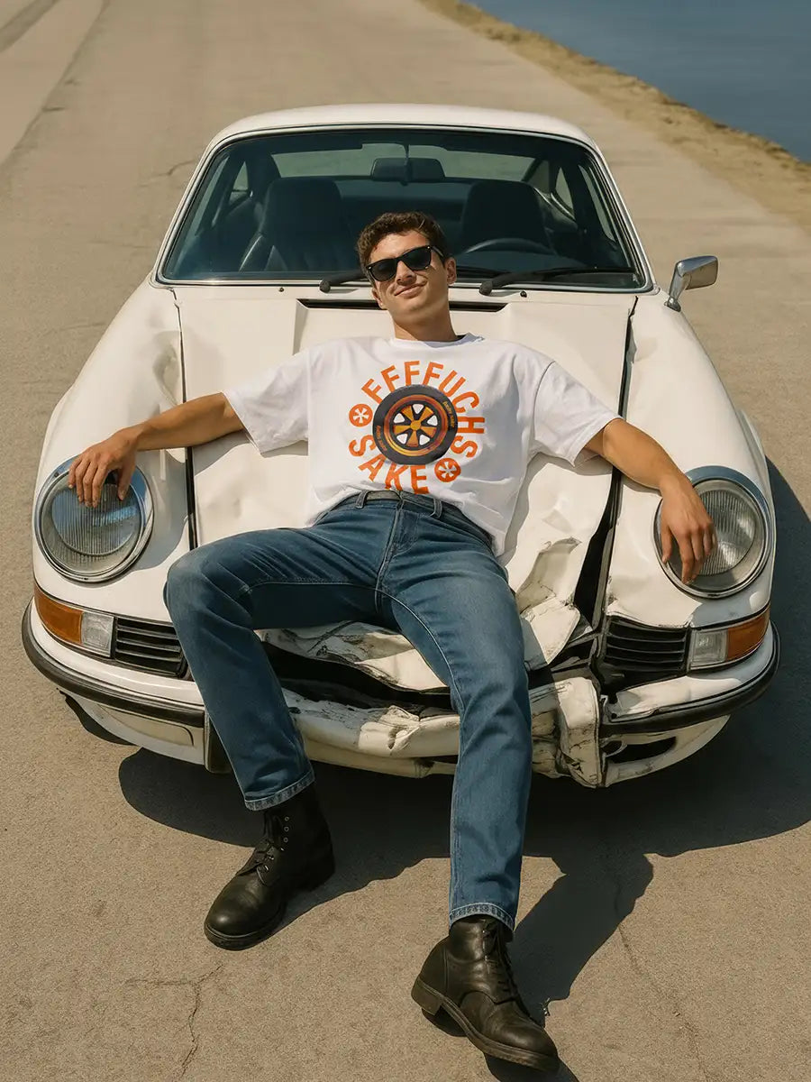 Person sitting on a wrecked porsche 911 with a white t-shirt and sunglasses