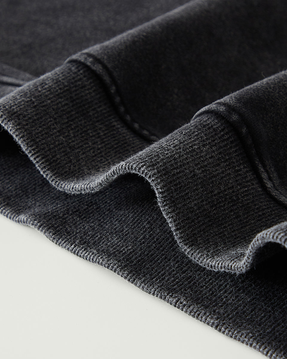 Close-up of dark gray fabric with a textured pattern on a light gray background