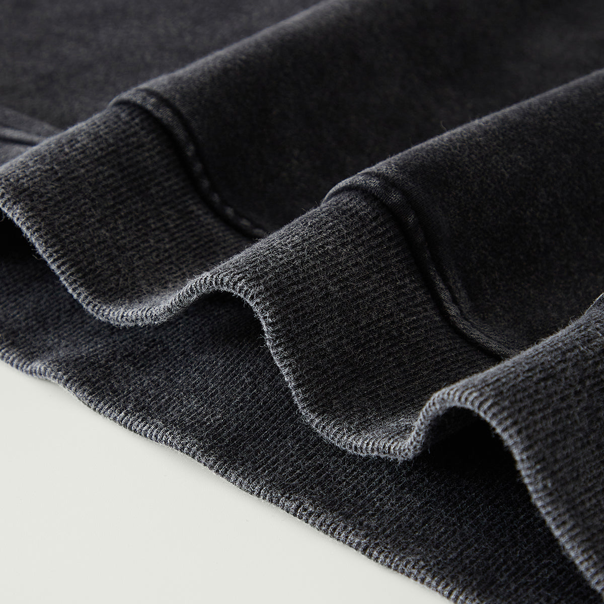 Close-up of dark gray fabric with a textured pattern on a light gray background