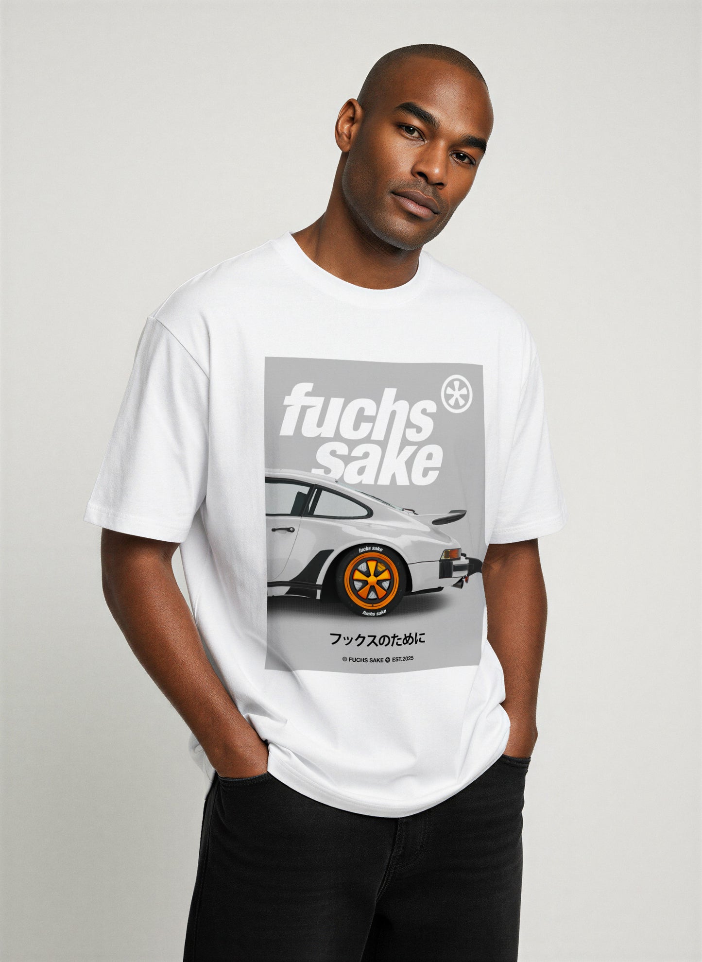 Man wearing white ‘fuchs sake’ T-shirt with Porsche 911 and Fuchs wheel print — premium automotive-inspired streetwear for Porsche lovers.