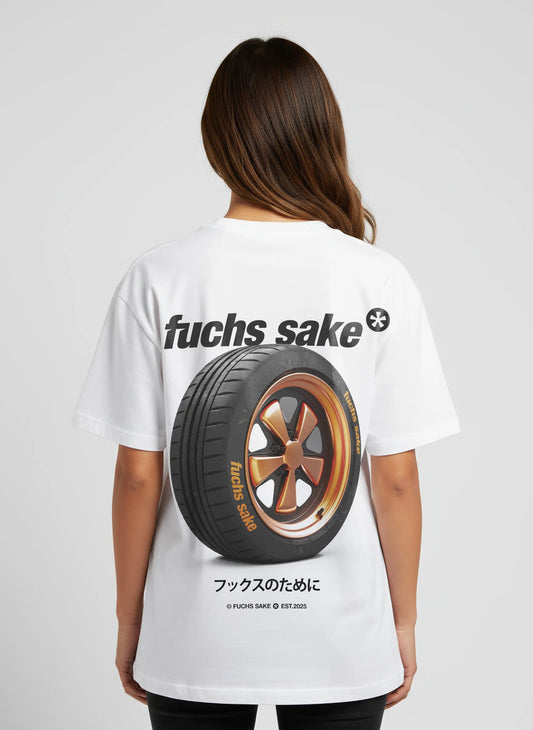 Back view of woman modeling white graphic tee with bronze Fuchs wheel design, ‘fuchs sake’ logo, and Japanese text — automotive streetwear for Porsche lovers.