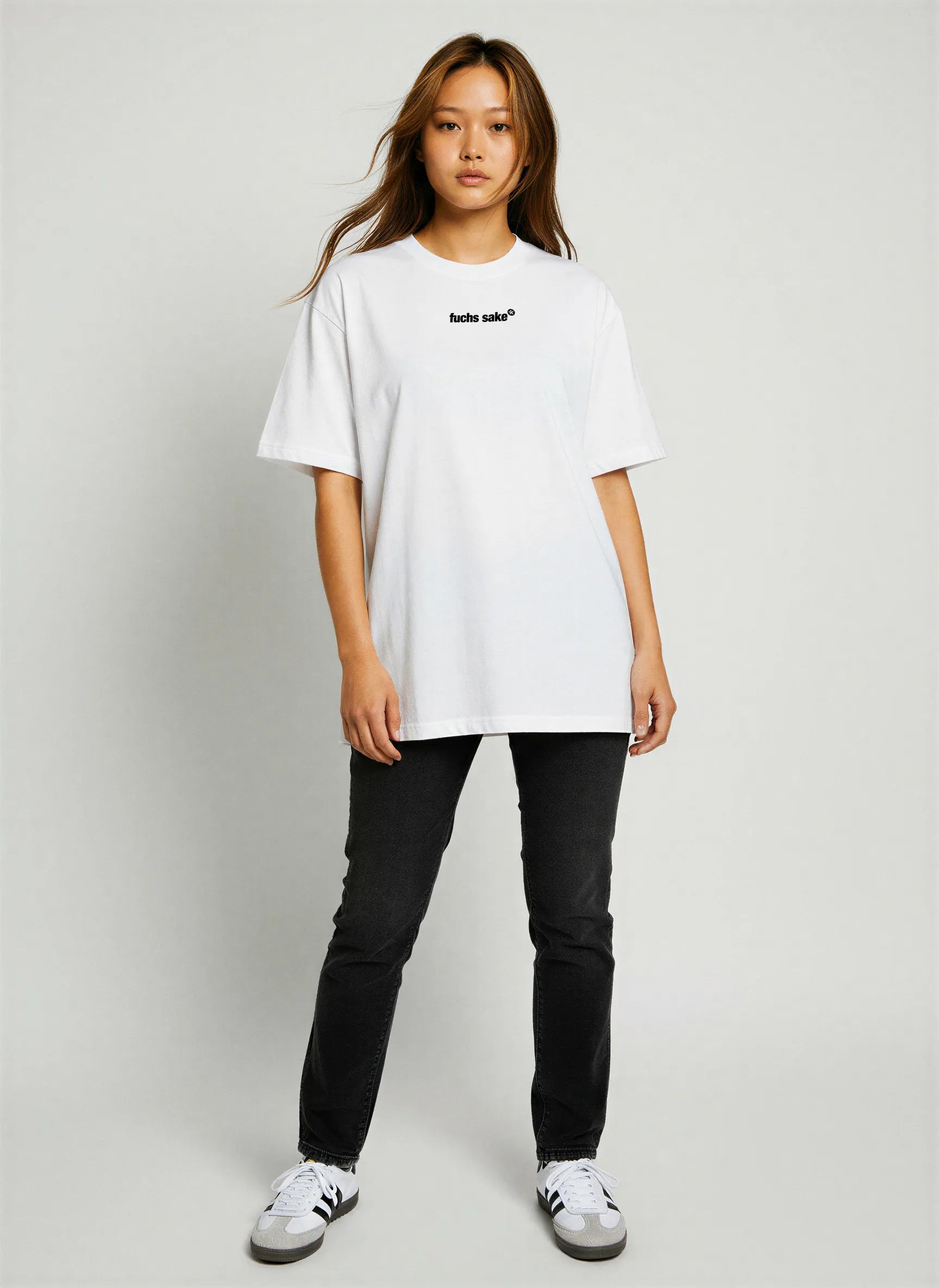Full-body view of woman in casual outfit wearing white ‘fuchs sake’ T-shirt with black jeans and sneakers — stylish Porsche-inspired graphic tee for automotive enthusiasts.