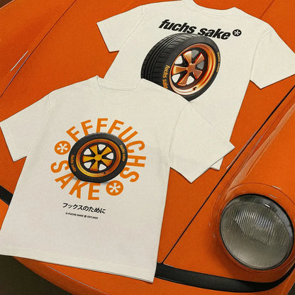 Two white t-shirts with orange and black graphics on an orange car background